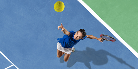 Image showing Young woman in blue shirt playing tennis. Youth, flexibility, power and energy.