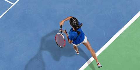 Image showing Young woman in blue shirt playing tennis. Youth, flexibility, power and energy.