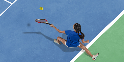 Image showing Young woman in blue shirt playing tennis. Youth, flexibility, power and energy.