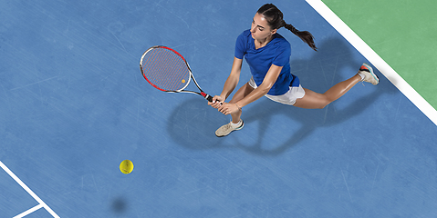 Image showing Young woman in blue shirt playing tennis. Youth, flexibility, power and energy.