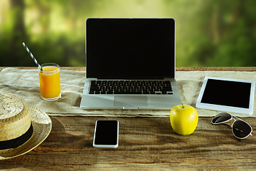 Image showing Blank laptop on a wooden table outdoors, mock up