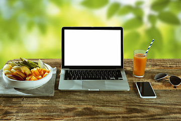 Image showing Blank laptop on a wooden table outdoors, mock up