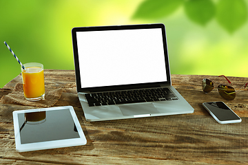 Image showing Blank laptop on a wooden table outdoors, mock up