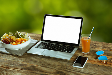 Image showing Blank laptop on a wooden table outdoors, mock up