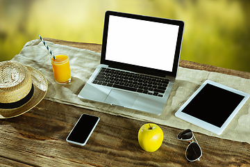 Image showing Blank laptop on a wooden table outdoors, mock up