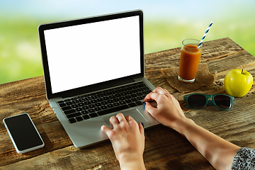 Image showing Blank laptop on a wooden table outdoors, mock up