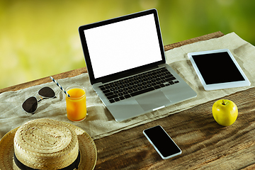 Image showing Blank laptop on a wooden table outdoors, mock up