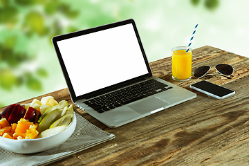 Image showing Blank laptop on a wooden table outdoors, mock up