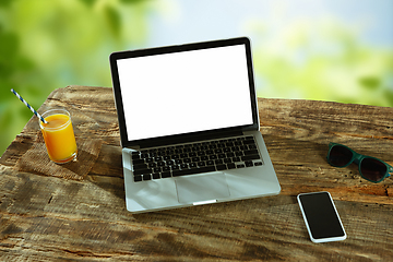 Image showing Blank laptop on a wooden table outdoors, mock up