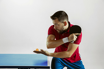 Image showing Young man playing table tennis on white studio background