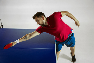 Image showing Young man playing table tennis on white studio background