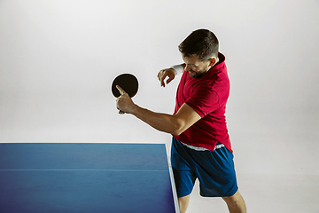 Image showing Young man playing table tennis on white studio background