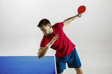 Image showing Young man playing table tennis on white studio background