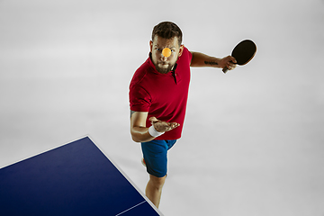 Image showing Young man playing table tennis on white studio background