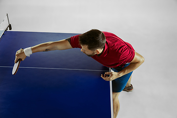 Image showing Young man playing table tennis on white studio background