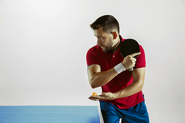 Image showing Young man playing table tennis on white studio background