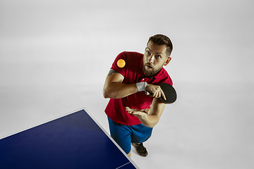 Image showing Young man playing table tennis on white studio background