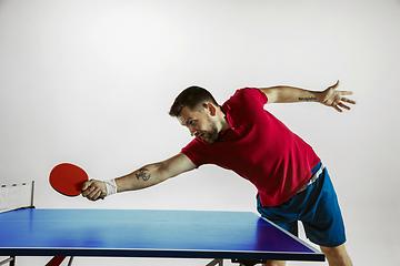 Image showing Young man playing table tennis on white studio background