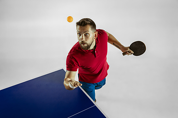 Image showing Young man playing table tennis on white studio background