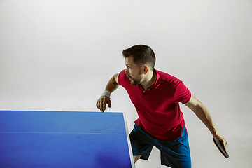 Image showing Young man playing table tennis on white studio background