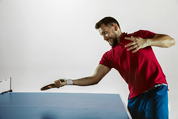 Image showing Young man playing table tennis on white studio background