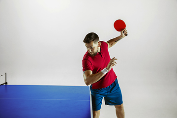 Image showing Young man playing table tennis on white studio background