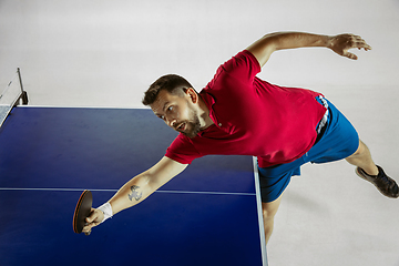 Image showing Young man playing table tennis on white studio background