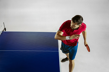 Image showing Young man playing table tennis on white studio background