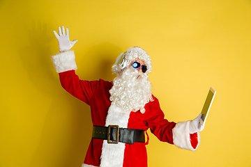 Image showing Santa Claus with modern gadgets isolated on yellow studio background