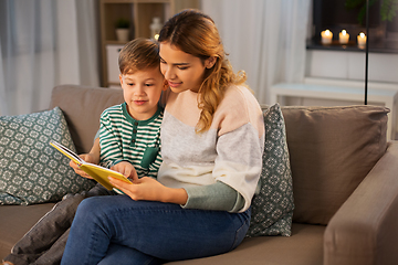 Image showing happy mother and son reading book sofa at home