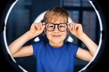 Image showing boy in glasses over illumination in dark room