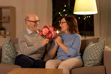 Image showing happy senior couple with bunch of flowers at home