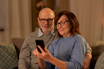 Image showing happy senior couple with smartphone at home