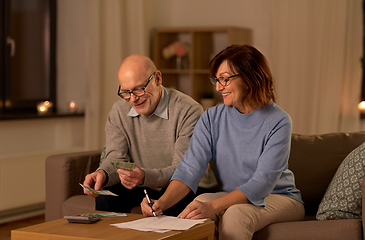 Image showing senior couple with bills counting money at home