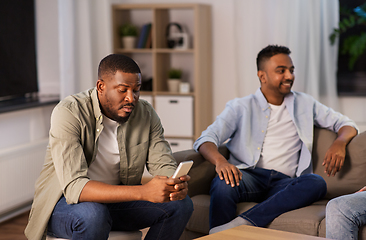 Image showing man using smartphone while friends talking at home