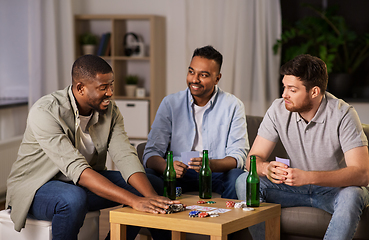 Image showing happy male friends playing cards at home at night