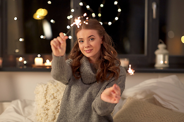 Image showing happy young woman with sparklers in bed at home