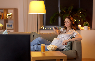 Image showing pregnant woman with remote control watching tv