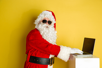 Image showing Santa Claus with modern gadgets isolated on yellow studio background