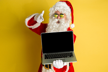 Image showing Santa Claus with modern gadgets isolated on yellow studio background