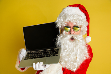 Image showing Santa Claus with modern gadgets isolated on yellow studio background