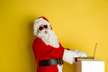 Image showing Santa Claus with modern gadgets isolated on yellow studio background