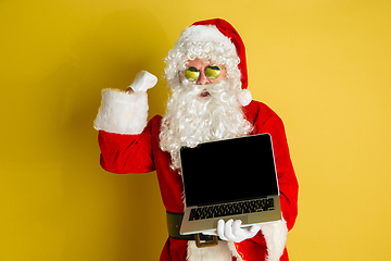 Image showing Santa Claus with modern gadgets isolated on yellow studio background