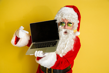 Image showing Santa Claus with modern gadgets isolated on yellow studio background