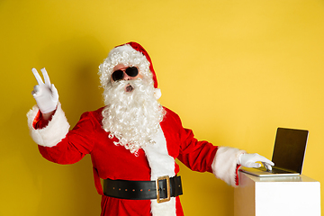 Image showing Santa Claus with modern gadgets isolated on yellow studio background