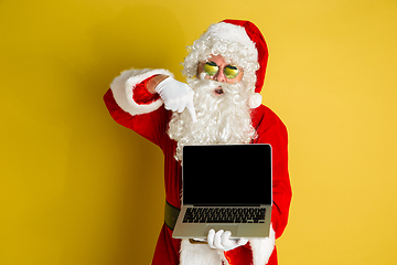 Image showing Santa Claus with modern gadgets isolated on yellow studio background