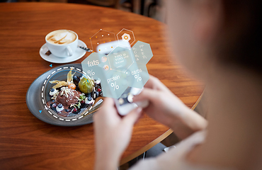 Image showing hands with phone and food nutritional value chart