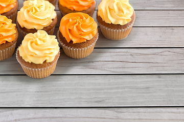 Image showing cupcakes with frosting on wooden boards background