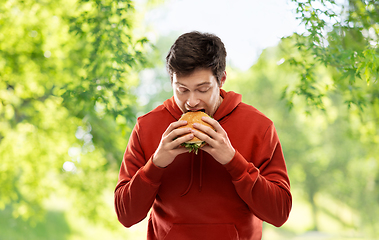 Image showing hungry young man eating hamburger