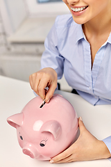 Image showing businesswoman with piggy bank and coin at office